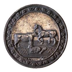 Medal with horse, bull, sheep, wheat sheaf and tools within grapevine border.