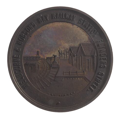 Round medal with railyard scene, text around.