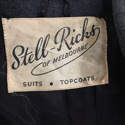 Details of white cloth label with black cursive lettering.