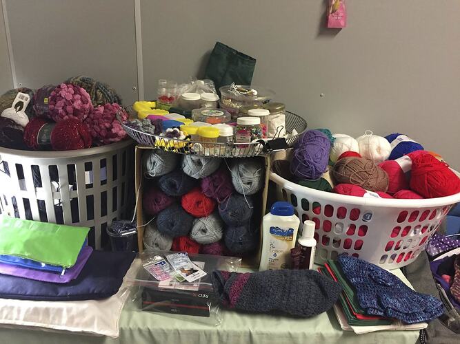 Two washing baskets and box overflowing with skeins of wool, yarn and craft items.