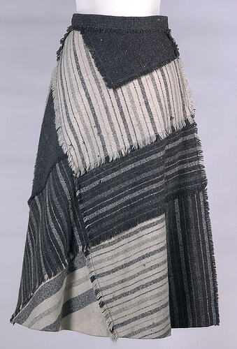 Grey skirt made of striped material patchworked together.