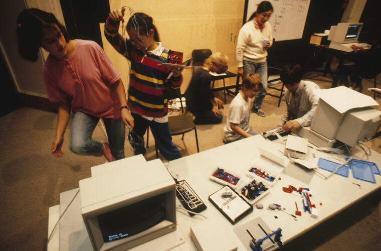 A classroom of students and teachers working with computers and Lego.