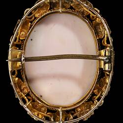 Back of oval brooch with gold framing white cameo relief. Frame is gold leaves and tendrils.