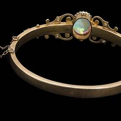 Back of gold bracelet with central oval white opal, supported by rose cut diamonds and delicate gold filigree-style detail.