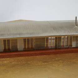 Model of a house with an arched roof, corrugated iron and wide expanses of glass.