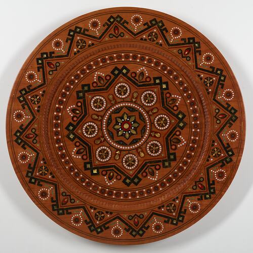 Round timber serving plate with detailed inlay work.