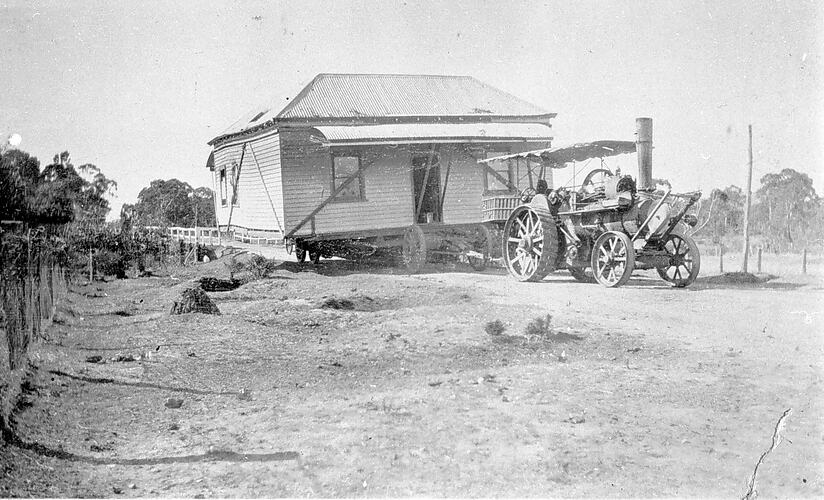 [A house being moved by a steam traction engine, near Kingower, about 1935. Although the house is supported by struts it is becoming distorted.]