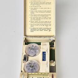 Rectangular cream metal case with four white labelled buttons. Open showing instructions and 2 spools.