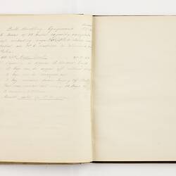 Open book with off white ruled pages. Handwritten text on left page.