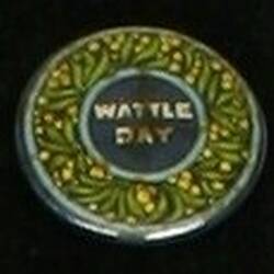 Circular badge with Border of golden wattle, And blue circle at centre with white text.