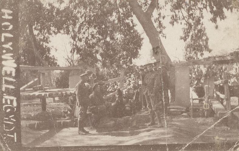 Group of servicemen standing outside with tress in background.