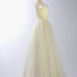 Side view, long cream evening gown, yellow sequins.