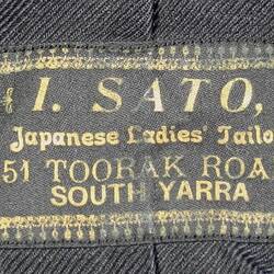 Black clothing label with name and adress of business in gold.