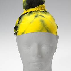Yellow tie-dyed and topknotted headscarf.