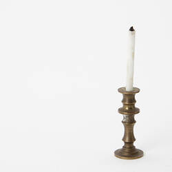 Brass coloured candle stick and white candle.