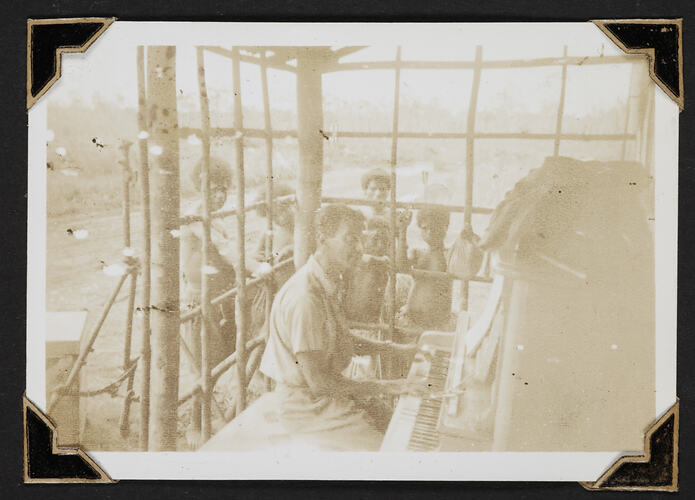 Man playing piano with children watching.