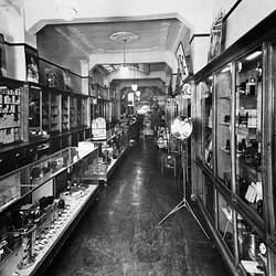 Interior of camera shop with display cases and counters lining walls.
