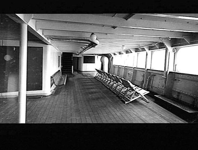 View of covered ship deck with row of deck chairs.
