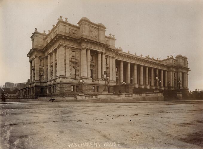 Grand building with columns. Multiple ornate street lamps out front.