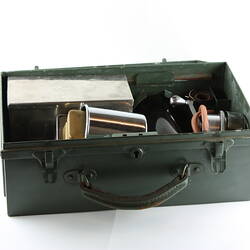 Khaki green metal case with carry handle, open with equipment inside.