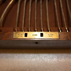 Detail of brass lock in wooden box. "ACME" text.