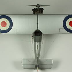 Silver model biplane model with red, white, blue rondels on wings and fuselage. Silver propeller. Top view.