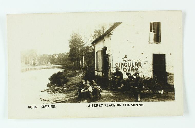 Soldiers sitting on the banks of a river next to a small building
