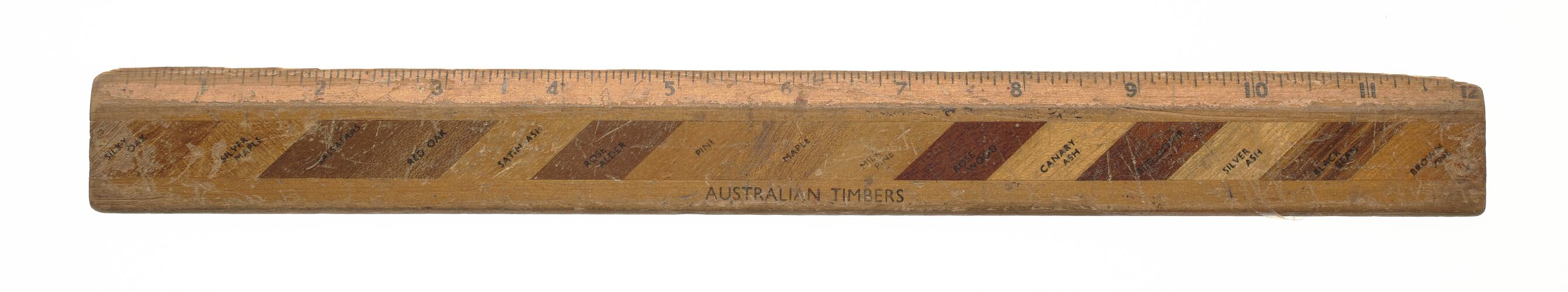 Wooden ruler with strips of different identified Australian timbers along length.