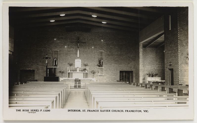 Interior of church with two rows of pews. Brick wall altar at far end.
