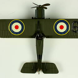 Dark green model airplane. Circle pattern on top on each wing. Aerial view.