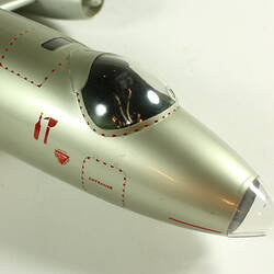 Silver model aeroplane. Detail of cockpit and nose.