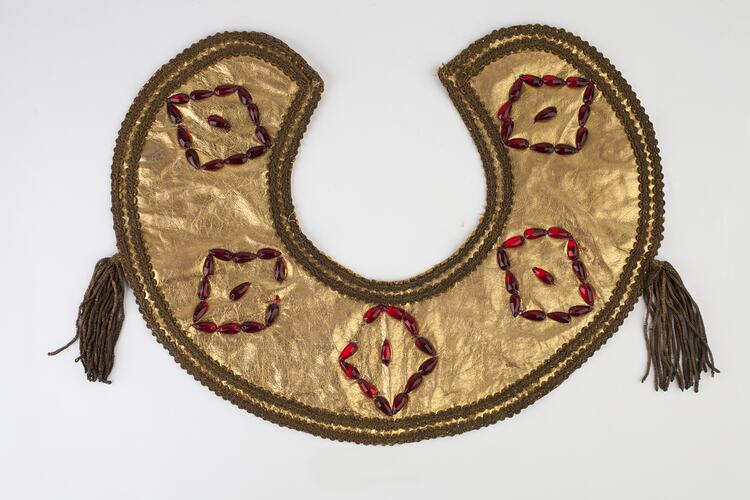 Round gold leather collar, red beaded detail, gold trim with two side gold tassels.