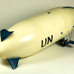 White model airship, blue nose and wings. Black UN on side. Rear right view.