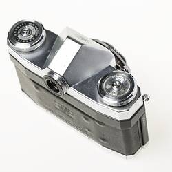 Black camera, metal top section, dials in each corner. Top view.