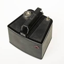 Black cube shaped all metal camera. Carry handle on the top plate. Top view.