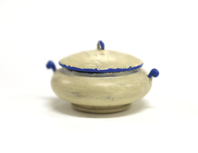 Side view of tiny white pot with lid.