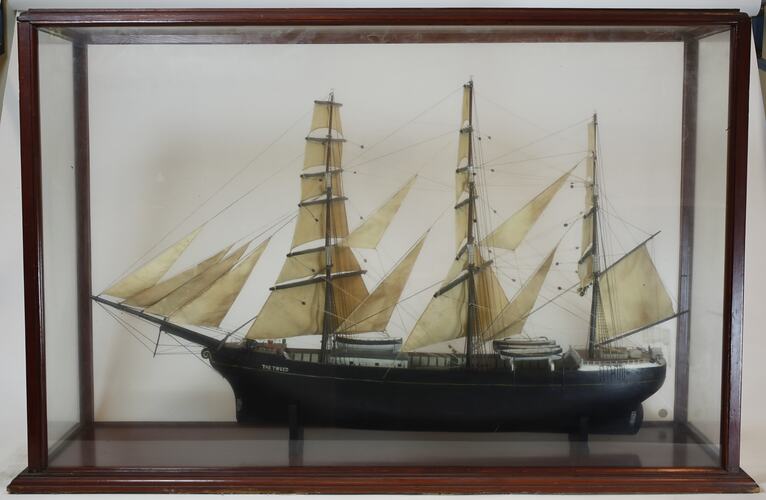 Sailing ship model in glass case, facing left.