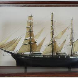 Sailing ship model in glass case, facing left.