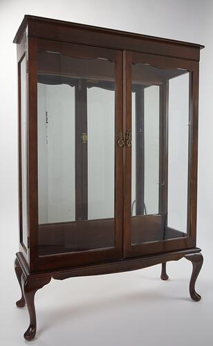 Wooden framed crystal cabinet. Glass doors and sides mirror at back. Wooden crystal cabinet. Front view.