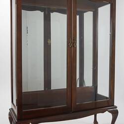 Wooden framed crystal cabinet. Glass doors and sides mirror at back. Wooden crystal cabinet. Front view.