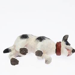 Black and white dog figurine with red collar and tongue. View from below.
