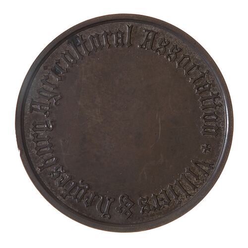 Round bronze medal with central blank section for engraving. Text around edge.