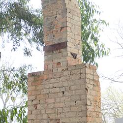 Red brick chimney. View from front and side, full height.