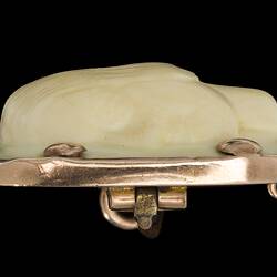 Profile of square cameo with rounded corners featuring a white female bust facing left, hair up in a bun. Four prominent corner gold pins secure the cameo to its gold setting.