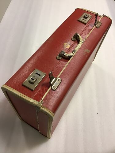 Top of closed red suitcase showing handle and locks.