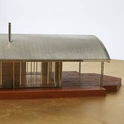 Model of a house with an arched roof, corrugated iron and wide expanses of glass.