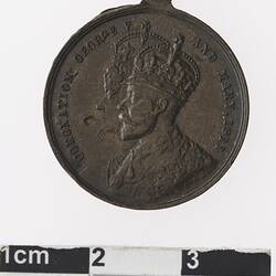 Round bronze coloured medal with profile of a crowned man and woman, text surrounding.