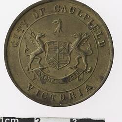 Round bronze coloured medal with coat of arms, text surrounding.
