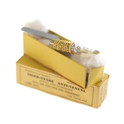 Yellow box with glass vial on cotton wool.