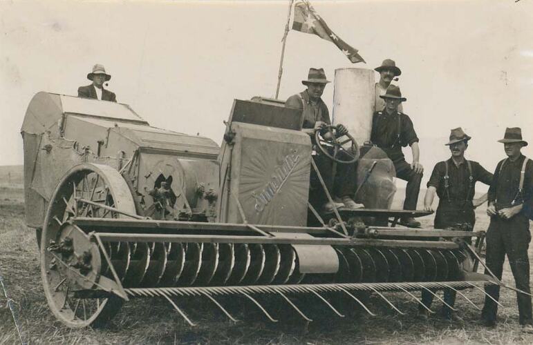 6 men sitting on Auto Header Harvester.